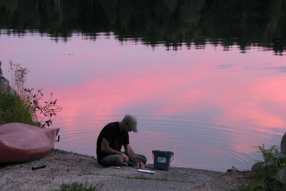Cleaning fish by Nicatous Lake at sunset.